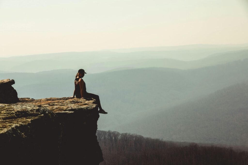 Woman sitting on the edge of a cliff in Winslow, Arkansas. For an article on Arkansas State Taxes.