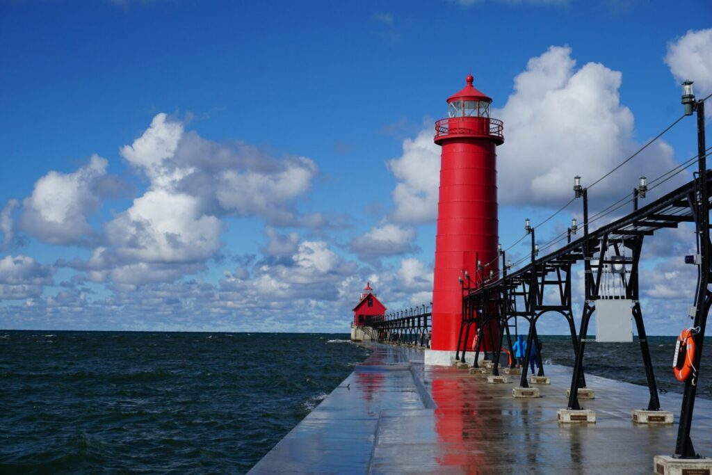 Red and white light house near a body of water
