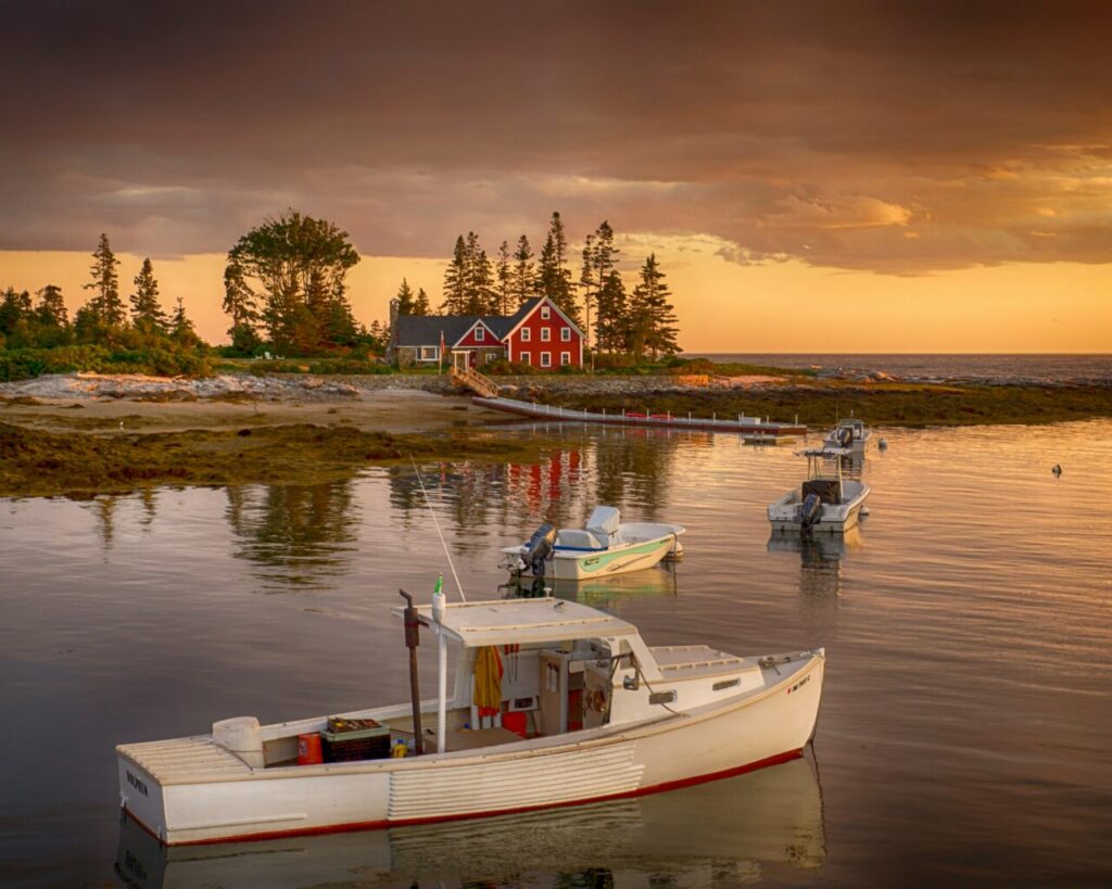 Red house beside body of water with white motor boats during the daytime