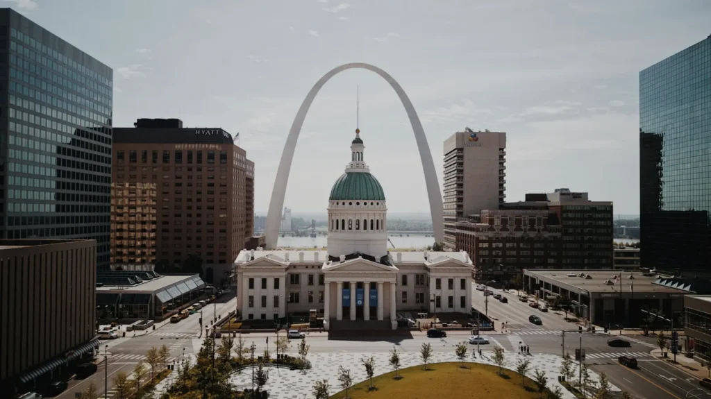 White and greend ome cathedral in between high rise buildings during daytime. Image of St. Louis, Missouri skyline for a blog article on MIssouri corporate state taxes.