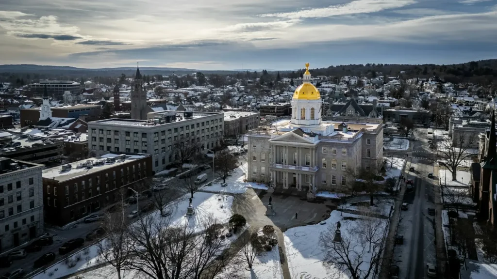 Aerial winter view of the New Hampshire State House in Concord, featuring its distinctive golden dome with a golden eagle statue. The historic capitol serves as the administrative seat for state matters including the New Hampshire corporate tax rate and business regulations.