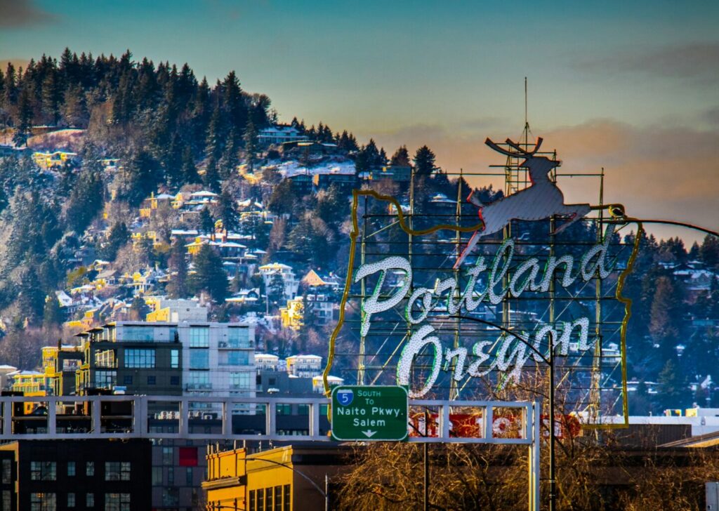 Sign that states Portland, Oregon with building in the background.